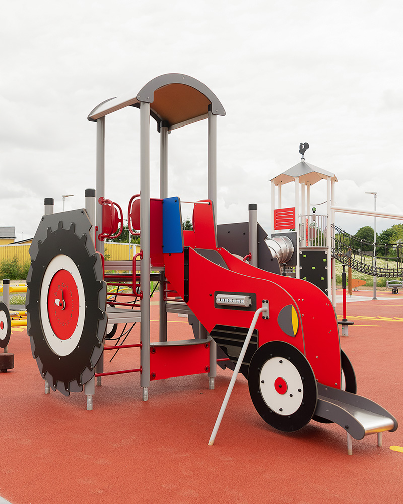 A tractor themed playground unit, it's red with a slide.